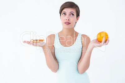 Woman choosing between pizza and an orange