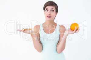 Woman choosing between pizza and an orange