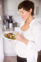 Pregnant woman having bowl of salad