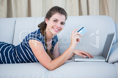 Pretty woman lying on couch doing online shopping