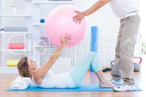 Therapist helping his patient with exercise ball