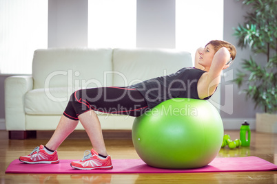 Fit woman doing sit ups on exercise ball