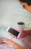 Woman using her smartphone and keyboard