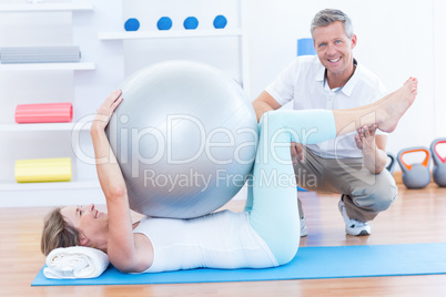 Therapist helping his patient with exercise ball