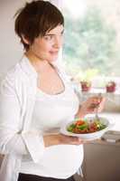 Pregnant woman having bowl of salad