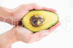 Woman holding half of an avocado