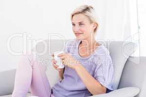 Pretty blonde woman relaxing on the couch and holding a mug