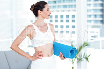 Smiling brunette holding exercise mat