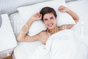 Relaxing woman in her bed smiling at camera