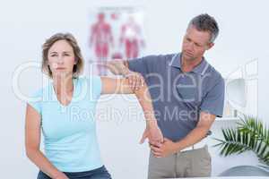 Woman stretching her arm with her doctor