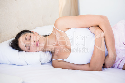 Pretty brunette with stomach pain on bed