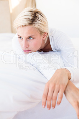 Thoughtful blonde woman lying on the bed