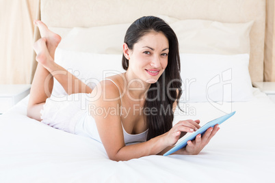 Pretty brunette touching tablet computer on couch