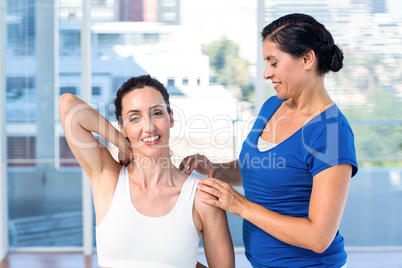 Woman stretching her arm with her therapist Woman stretching her arm with her therapist