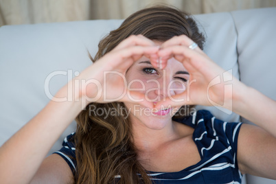 Smiling brunette making heart with her hands