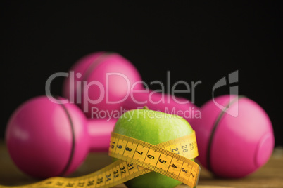 Pink dumbbells with green apple and measuring tape