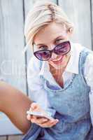 Pretty blonde woman wearing sun glasses and texting with her mob