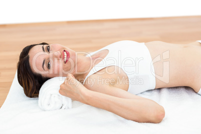 Smiling brunette lying on mat