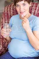 Pregnant woman taking a vitamin tablet