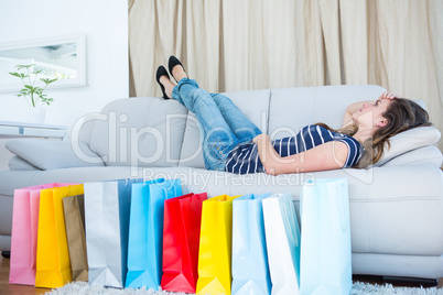 Pretty woman lying on couch near shopping bags