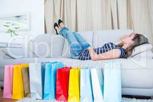 Pretty woman lying on couch near shopping bags
