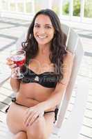 Pretty brunette sitting on a chair and drinking cocktail