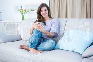 Happy brunette on couch smiling at camera