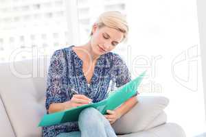 Pretty blonde woman taking notes on the couch