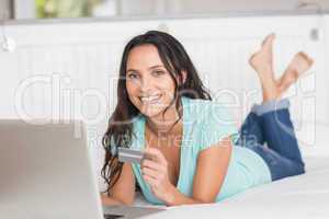 Happy brunette shopping online with laptop