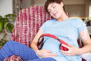 Pregnant woman putting headphones over bump