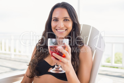 Pretty brunette sitting on a chair and drinking cocktail