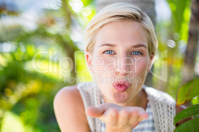 Pretty blonde woman smiling at the camera and blowing kiss