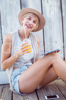 Pretty blonde woman using her tablet and holding orange juice