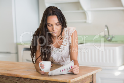 Pretty brunette reading newspaper with a mug