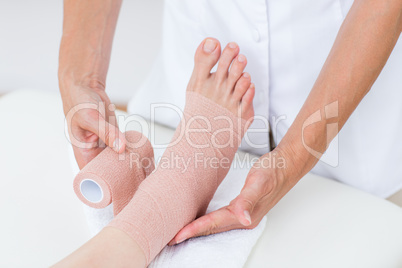 Doctor bandaging her patient ankle