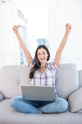 Happy pretty brunette looking at camera and using laptop