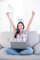 Happy pretty brunette looking at camera and using laptop