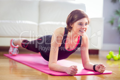 Fit woman doing plank on mat
