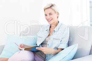 Pretty blonde woman reading a magazine on the couch