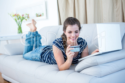 Pretty woman lying on couch doing online shopping