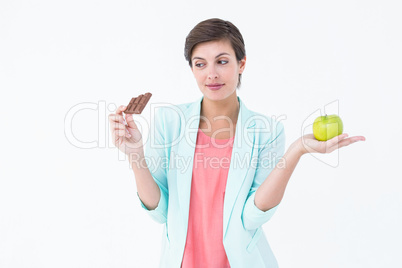 Brunette choosing between an apple and chocolate bar