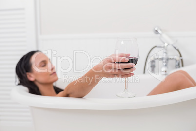 Pretty brunette taking a bath with glass of wine