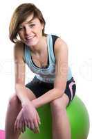 Pretty brunette looking at camera and smiling on fitness ball