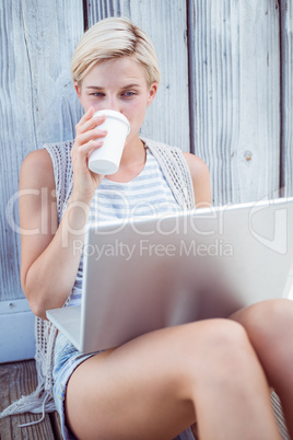 Pretty blonde woman using her laptop and drinking coffee