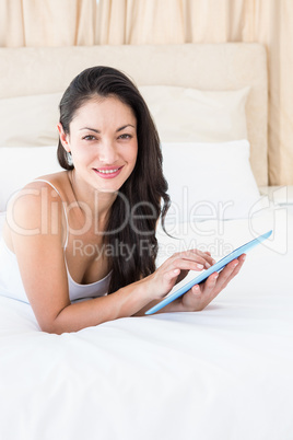 Pretty brunette touching tablet computer on couch