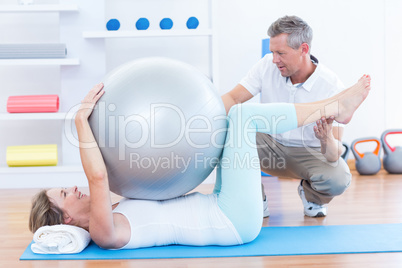 Therapist helping his patient with exercise ball Therapist helping his patient with exercise ball