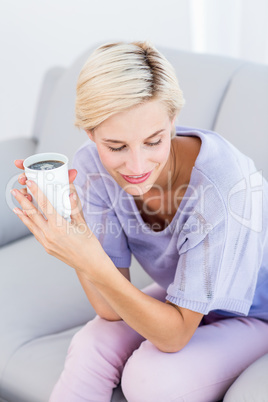 Pretty blonde woman relaxing on the couch and holding a mug