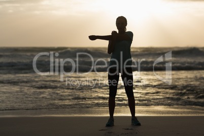 Sporty brunette stretching on the beach