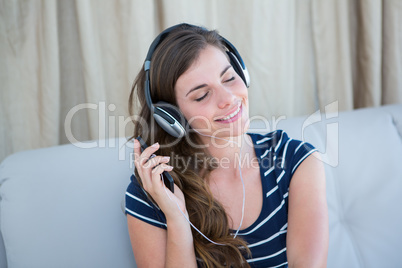 Pretty brunette listening music on couch