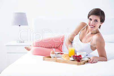 Happy brunette having her breakfast in bed